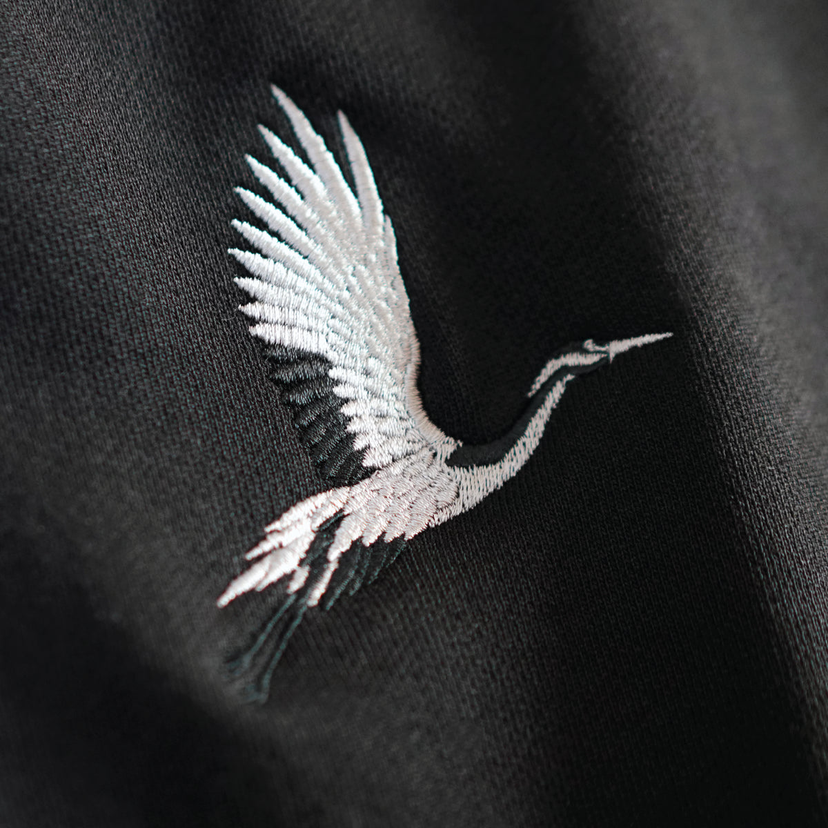 Detailed crane embroidery on black French terry