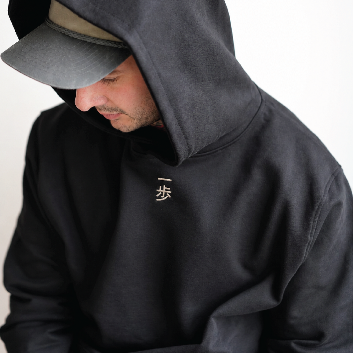 KyoPace Hoodie in Black, worn with the hood up over a cap