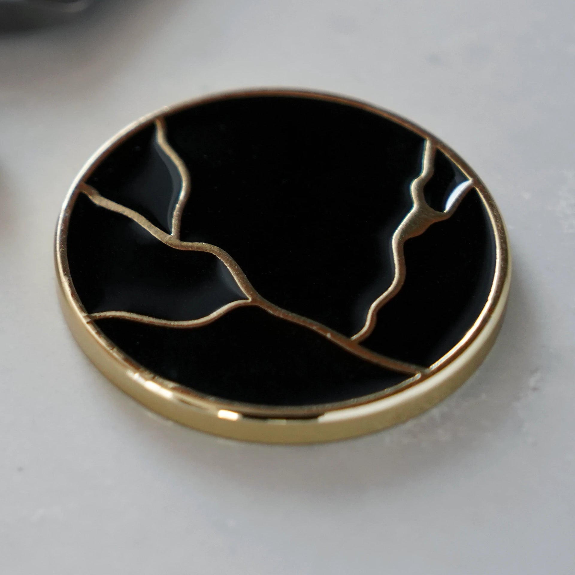ODAAT Medallion — Kintsugi Edition reverse side, featuring gold-plated kintsugi crack design on a glossy black background.