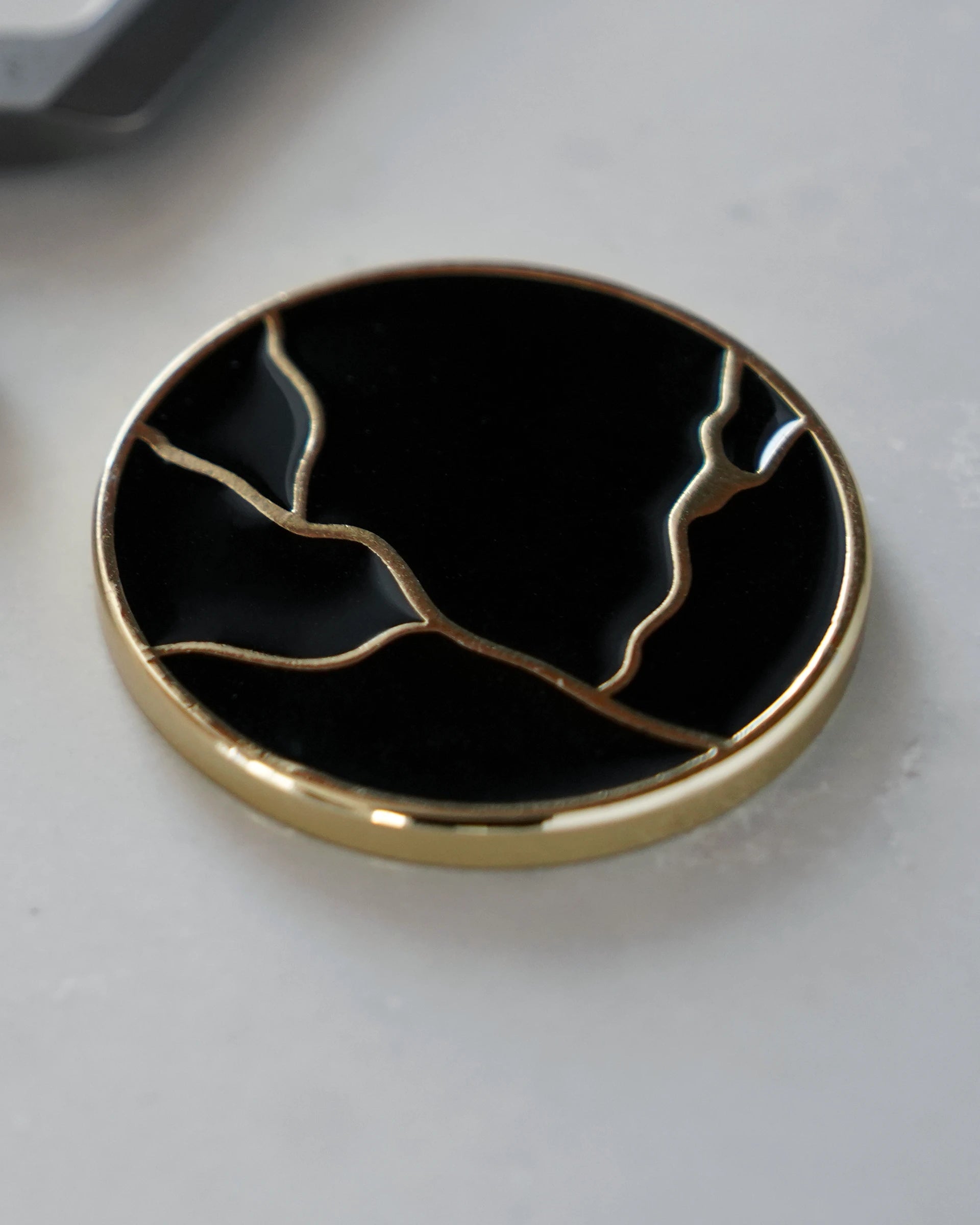ODAAT Medallion — Kintsugi Edition reverse side, featuring gold-plated kintsugi crack design on a glossy black background.