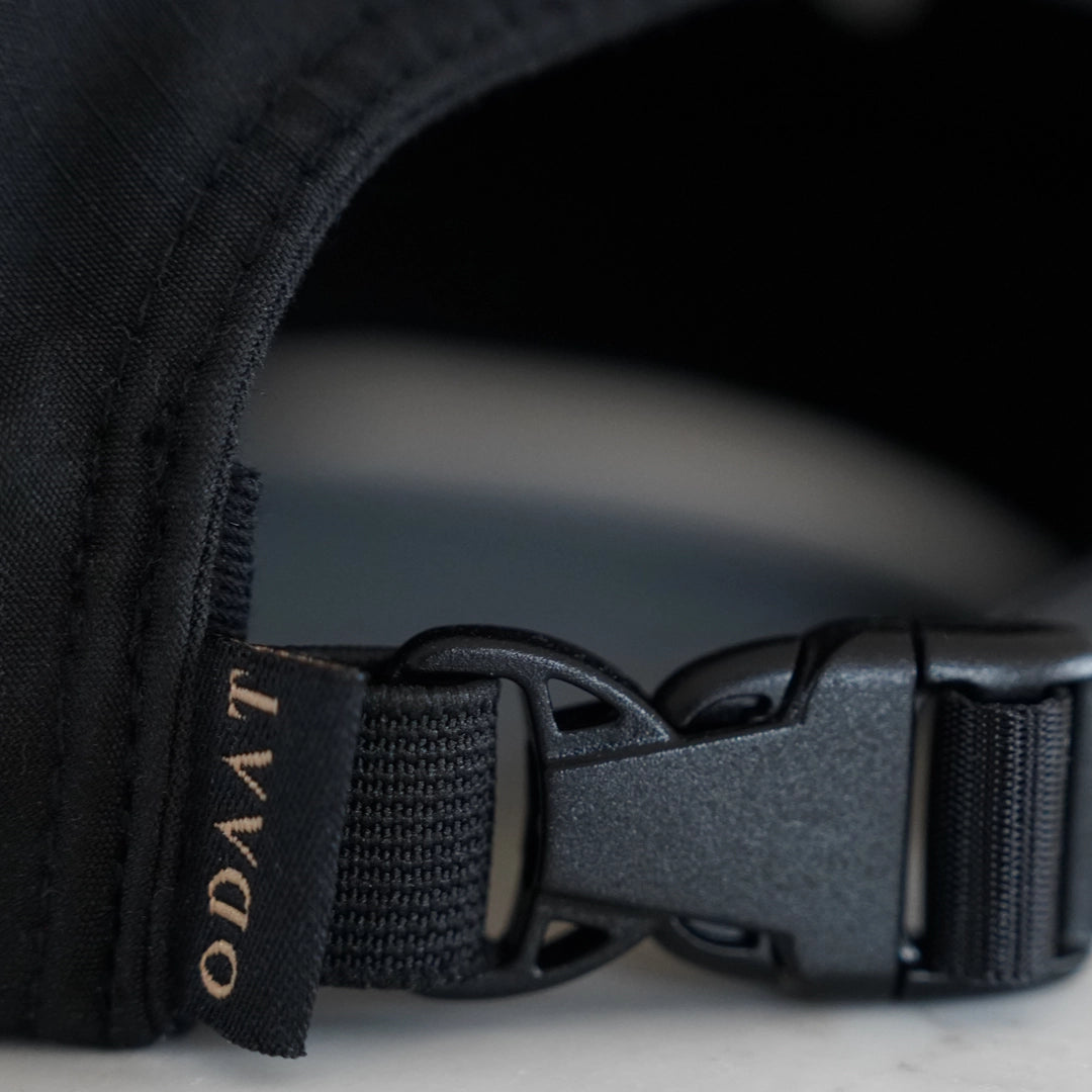 Close-up of the Progress Over Perfection Hat’s adjustable elastic-backed buckle and gold ochre ODAAT woven label—designed for a secure, flexible fit.