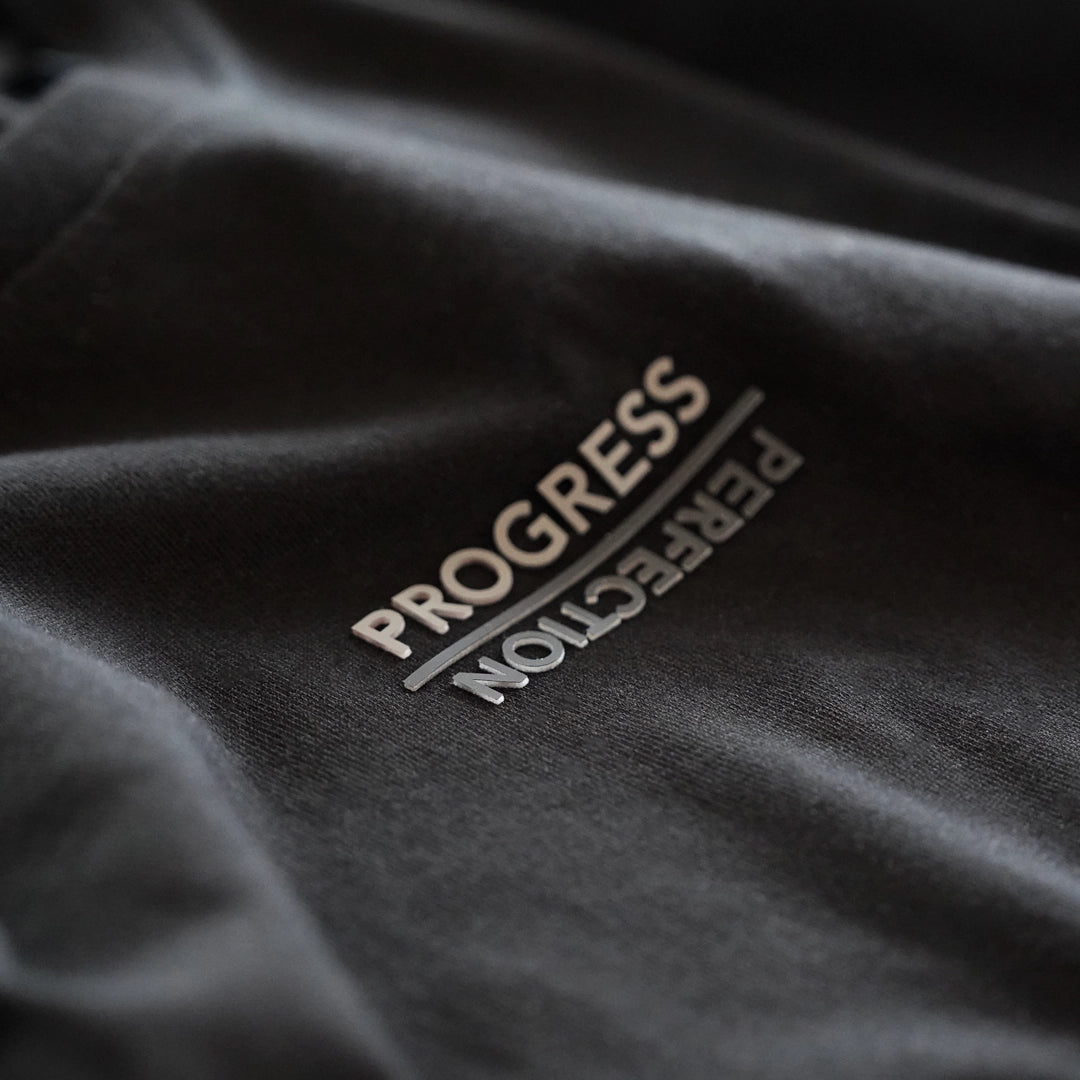 Close-up of the Progress Over Perfection Tee featuring raised tactile print with the words ‘Progress’ and ‘Perfection’ separated by a line—designed as a reminder that showing up matters more than flawless outcomes.