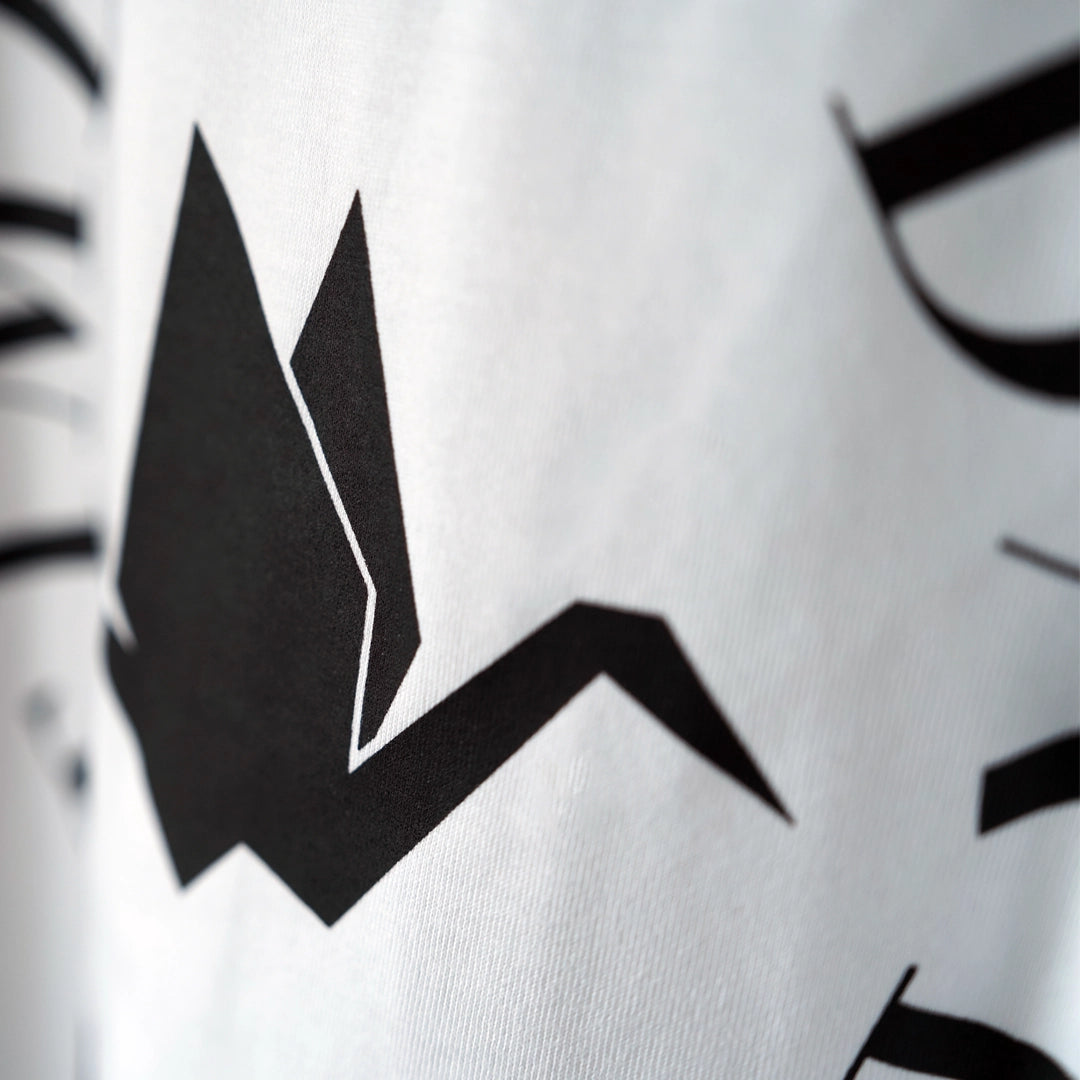 Close-up detail of black origami crane graphic on white ODAAT Apparel t-shirt — symbolic logo representing hope, healing, and resilience, part of the ‘One Day At A Time’ Circle of Resilience design.