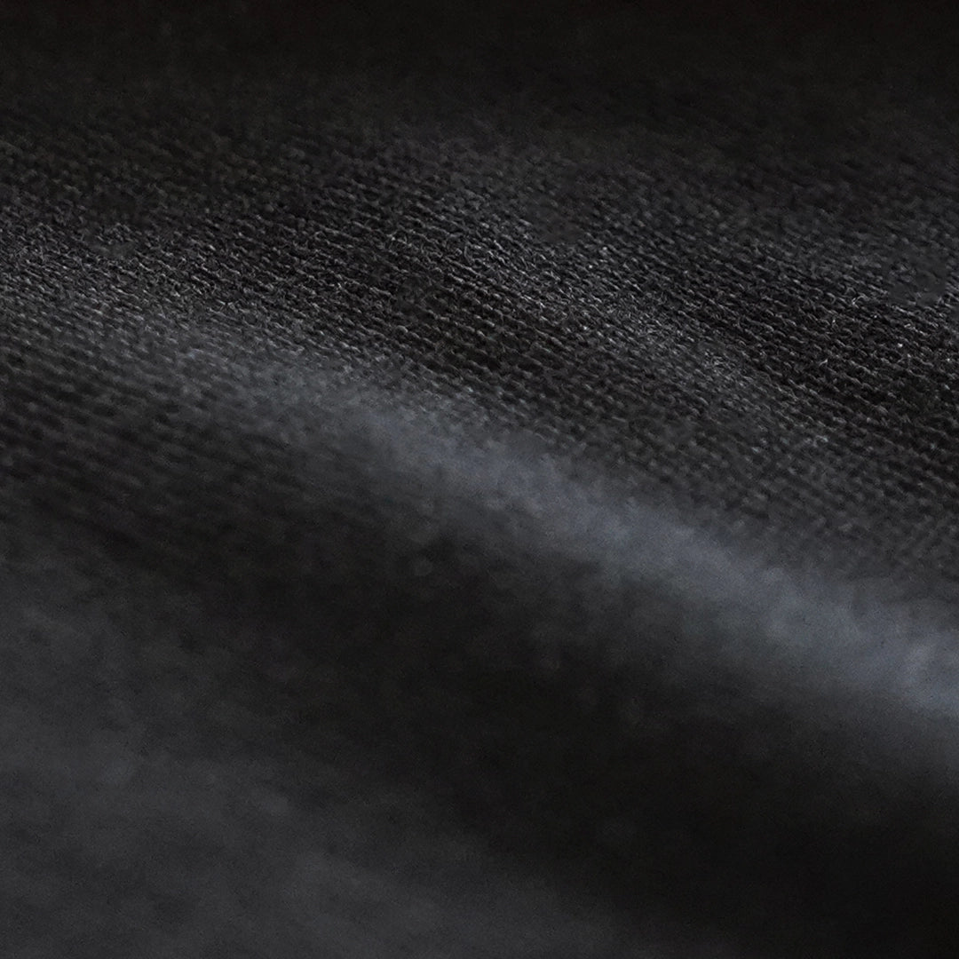 Macro close-up of ODAAT’s black organic cotton fabric, highlighting its dense, breathable weave—crafted for comfort, resilience, and longevity.