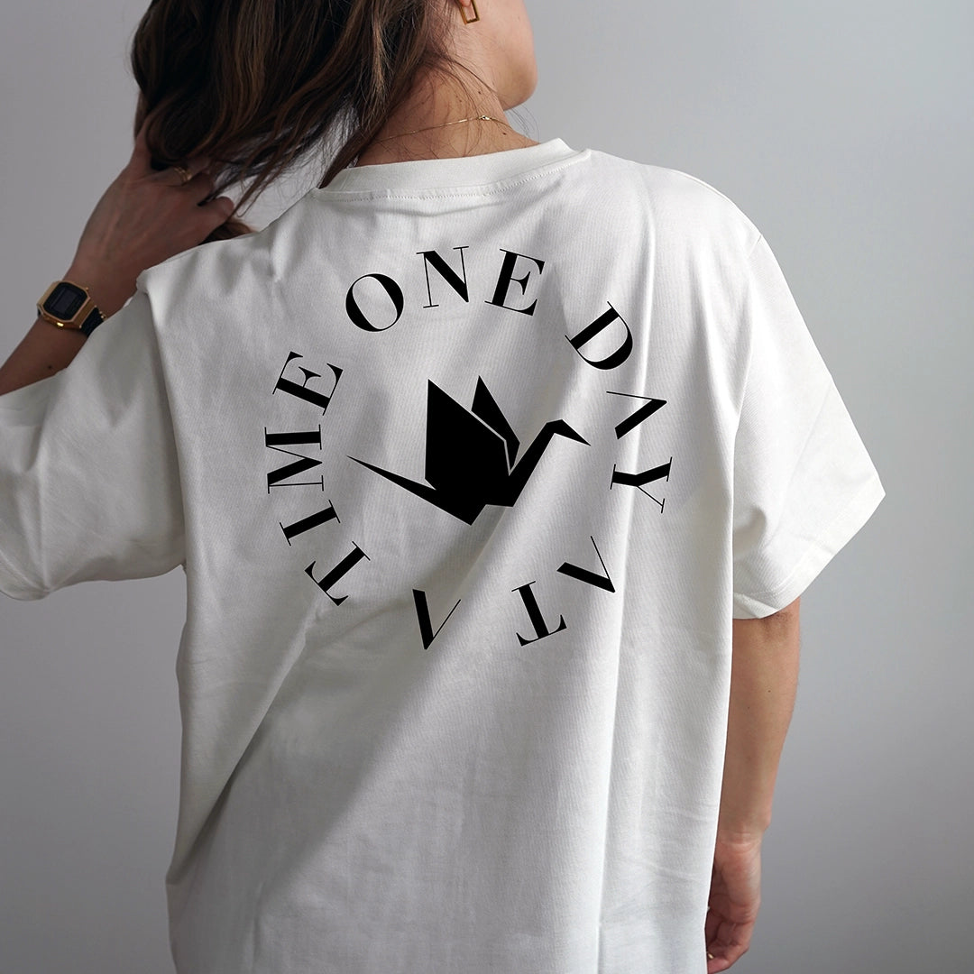White Circle of Resilience t-shirt featuring black circular ‘One Day At A Time’ text with minimalist origami crane logo at center, symbolizing hope and strength — ODAAT Apparel graphic tee for sobriety, resilience, and intentional living.