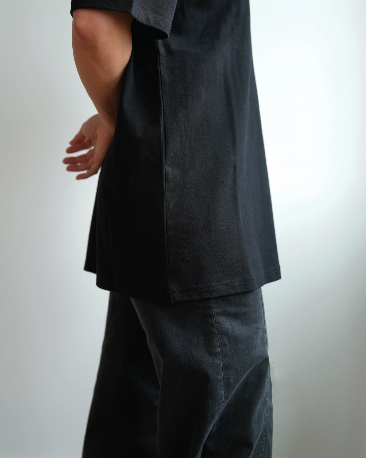 Midweight Tee in Black, side view, worn with dark trousers