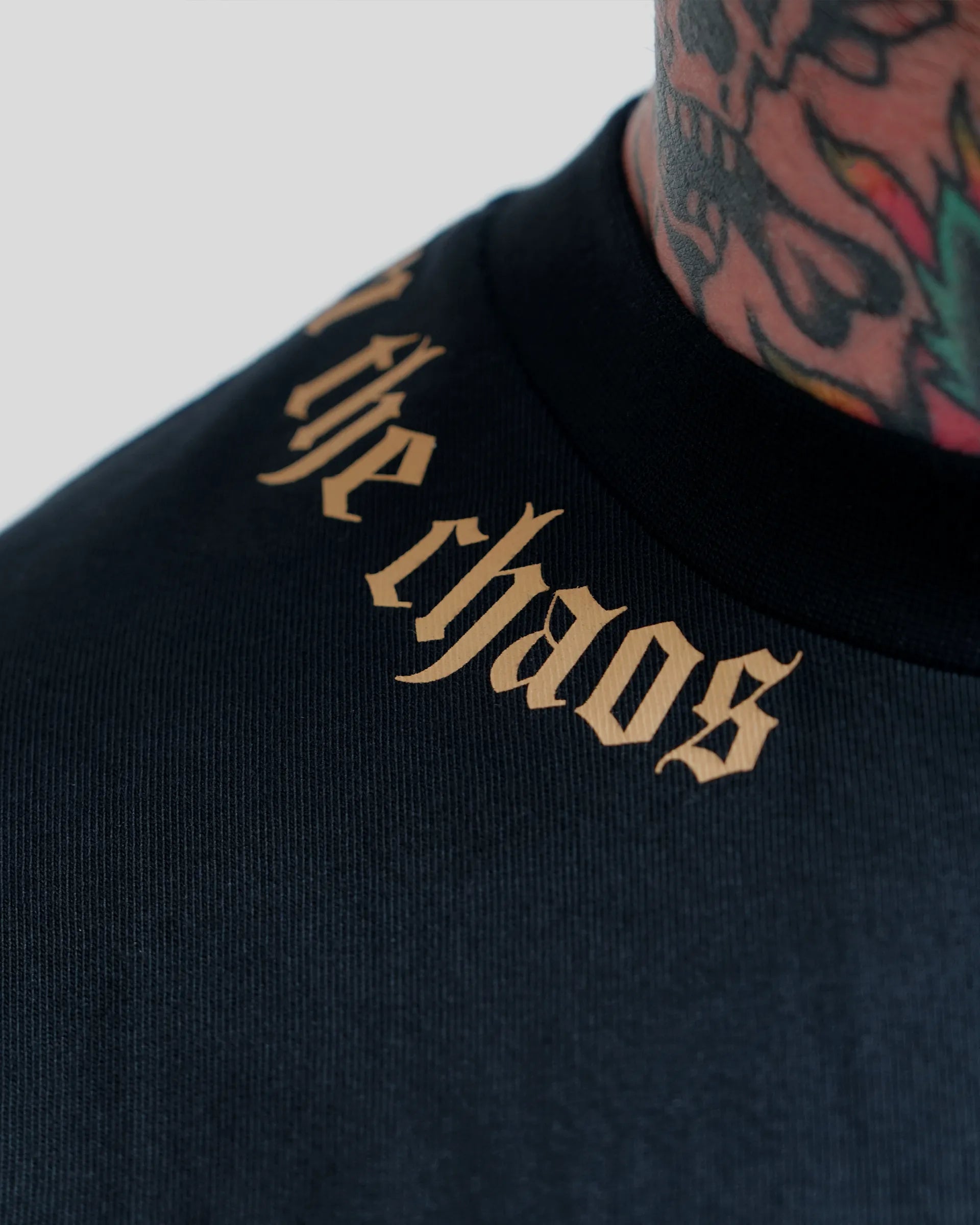 Calm in the Chaos boxy cropped tee in black with gold neckline graphic, front close-up