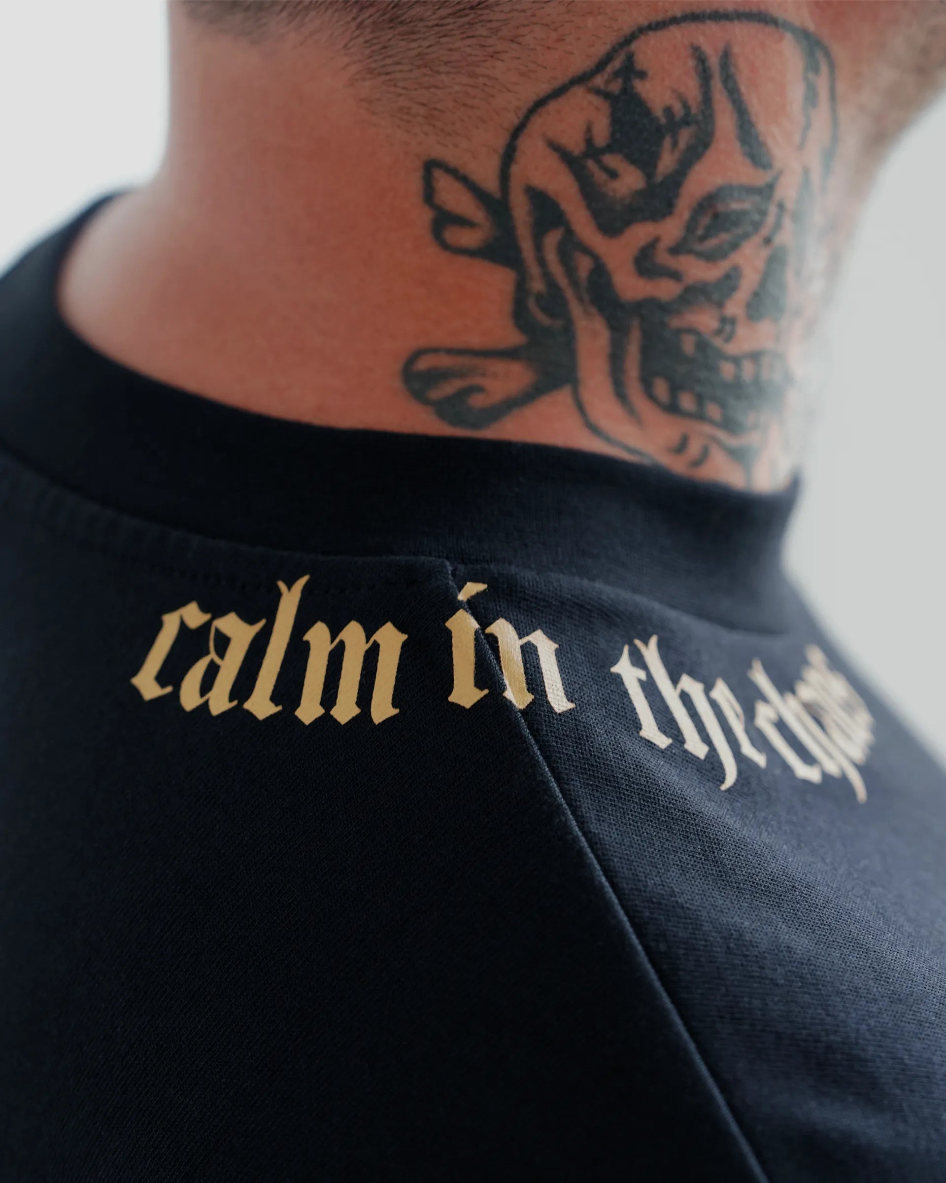 Close-up of Calm in the Chaos boxy cropped tee in black with gold neckline graphic