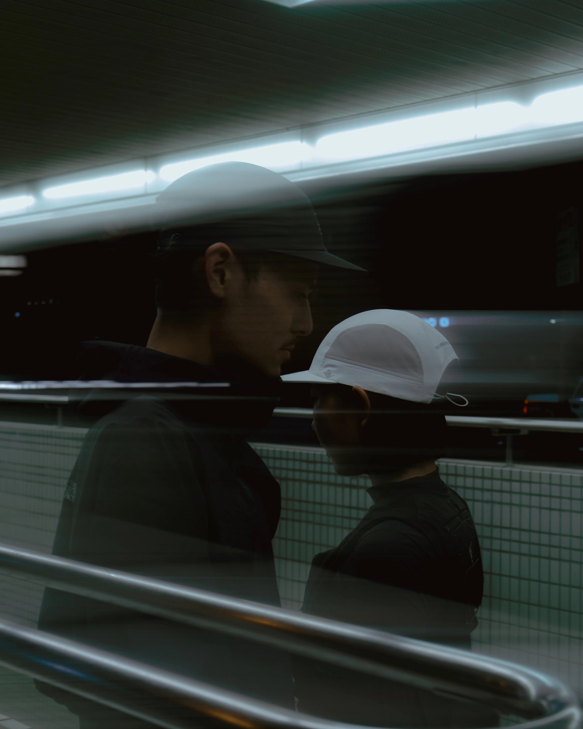 Two runners wearing black and white KyoPace running caps in motion with light streaks at night