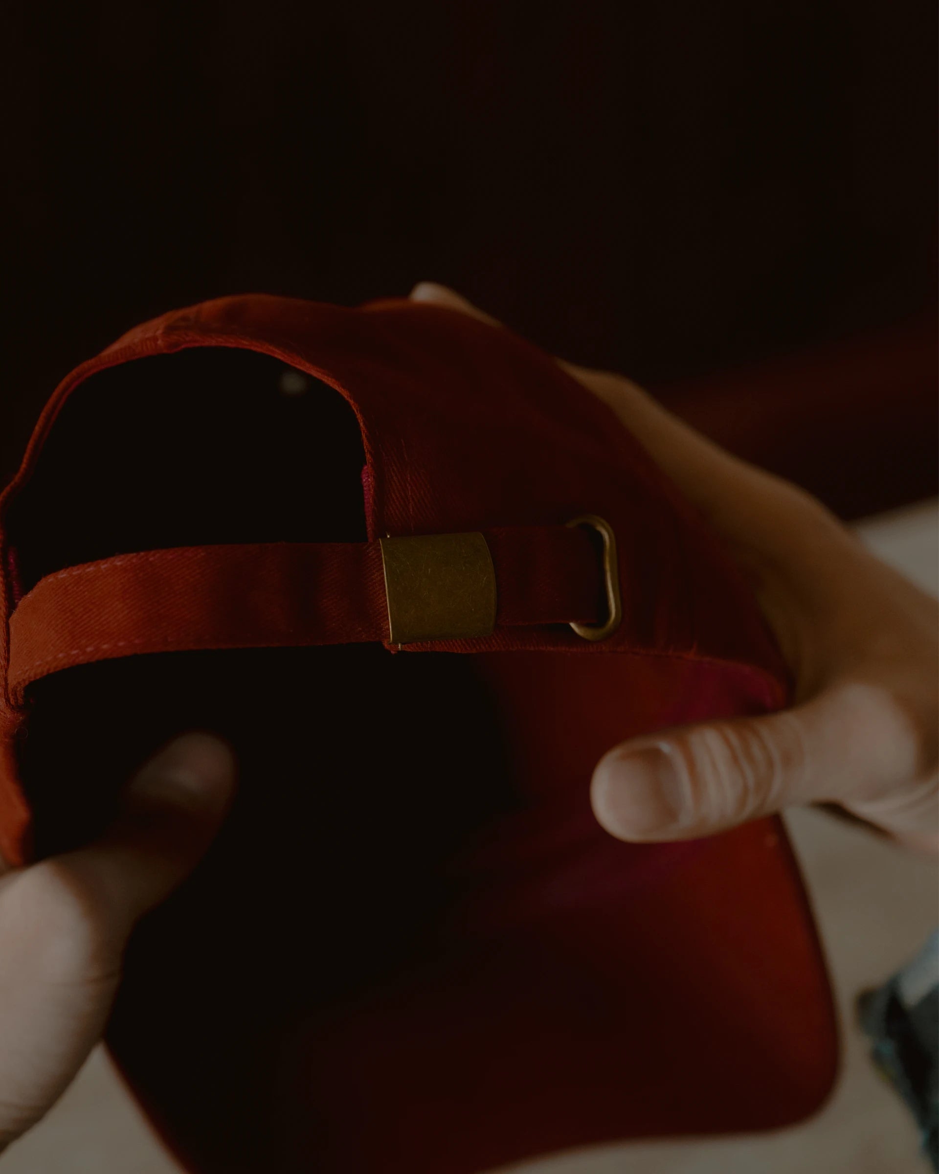 burgundy signature dad cap rear detail showing self-fabric strap and metal adjuster, soft cotton construction with clean stitching, close-up product shot with warm tonal lighting