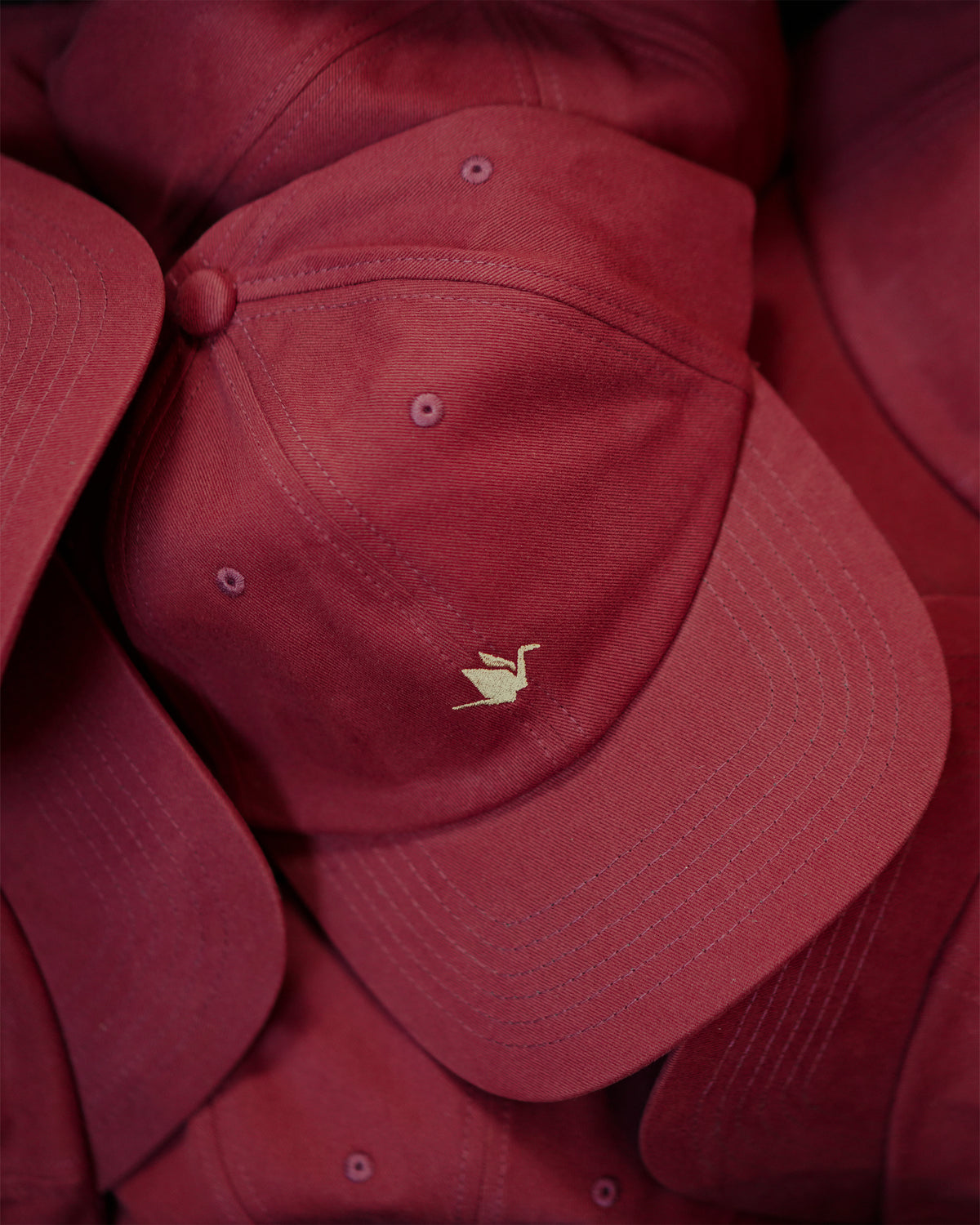 ODAAT Icon Cap in Burgundy, stacked caps showing the brushed cotton, curved brim and cream Orizuru embroidery.