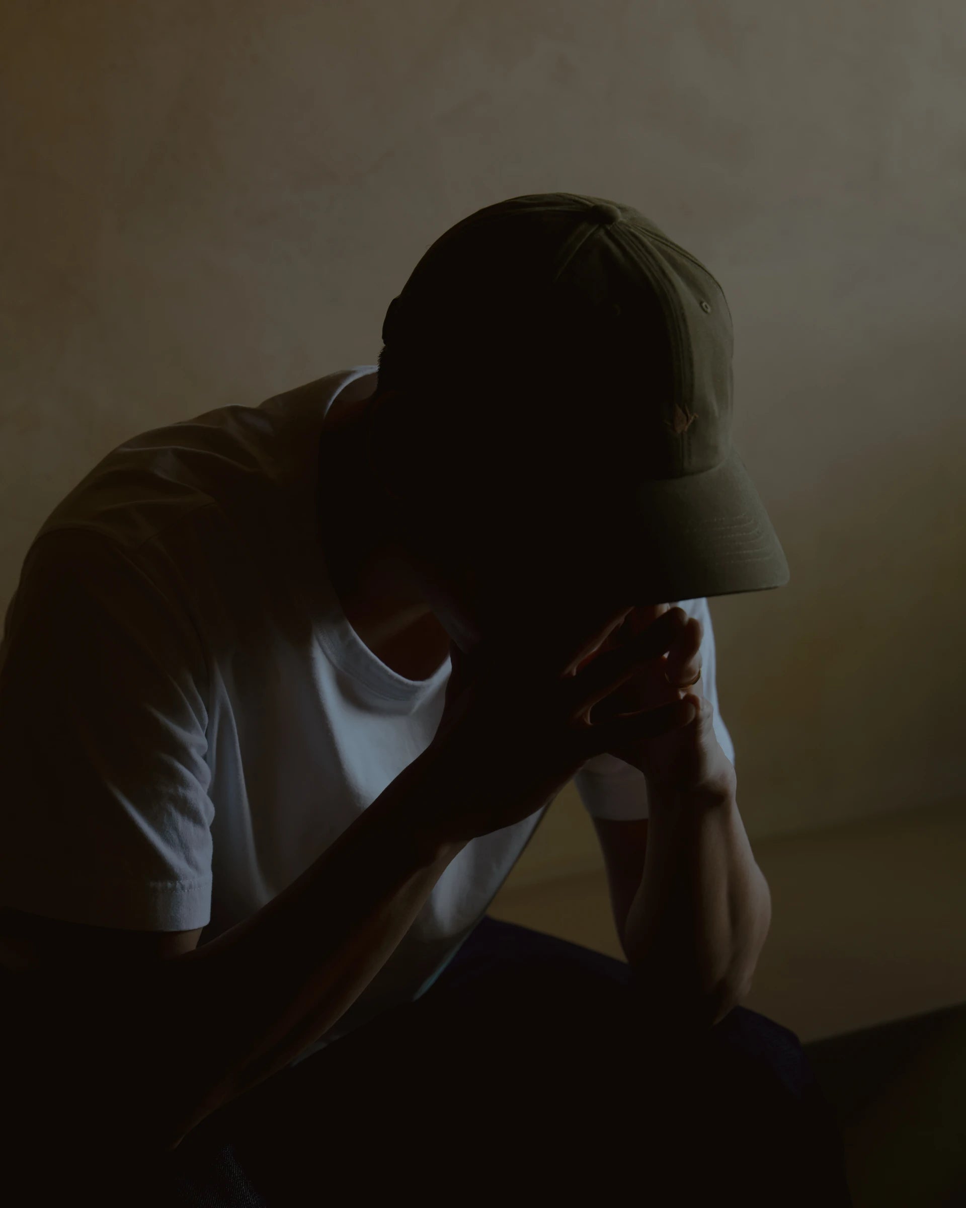 olive signature dad cap worn low in shadowed lifestyle portrait, soft cotton hat with curved brim and crane embroidery, minimal composition with warm light and muted tones