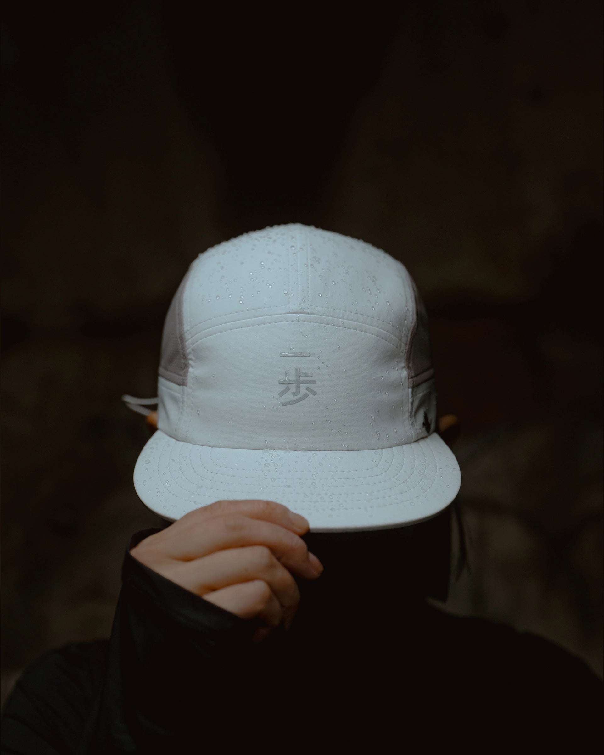 White KyoPace running cap with kanji, front view, worn by model partially covering face