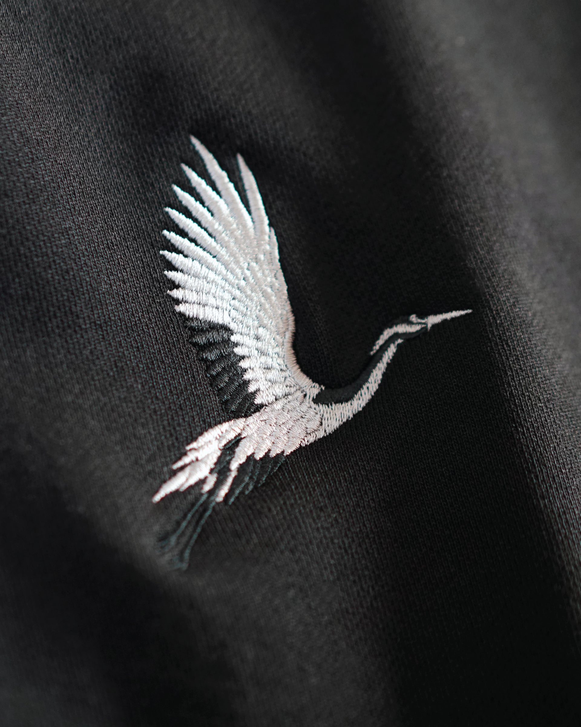 Detailed crane embroidery on black French terry