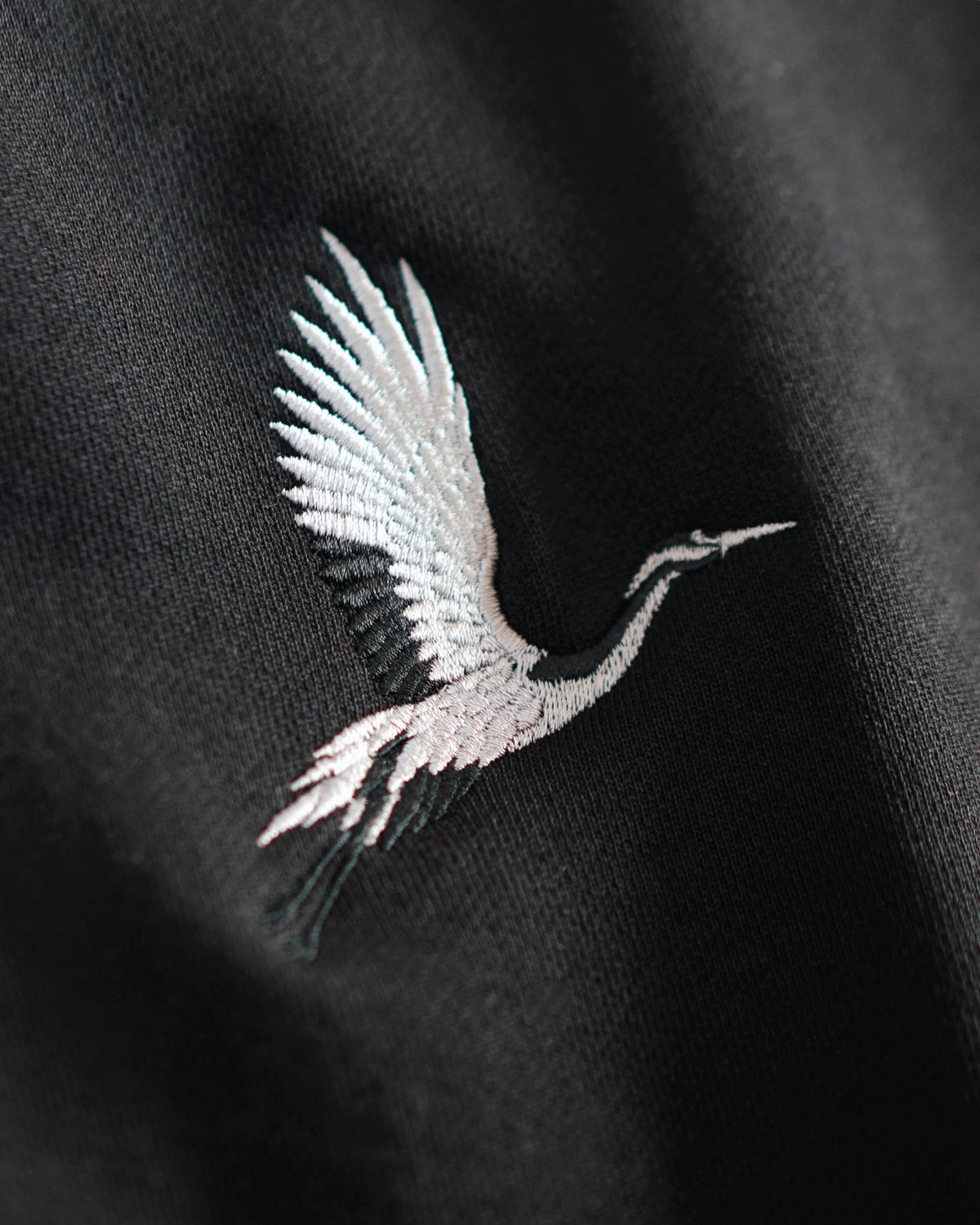 Detailed crane embroidery on black French terry