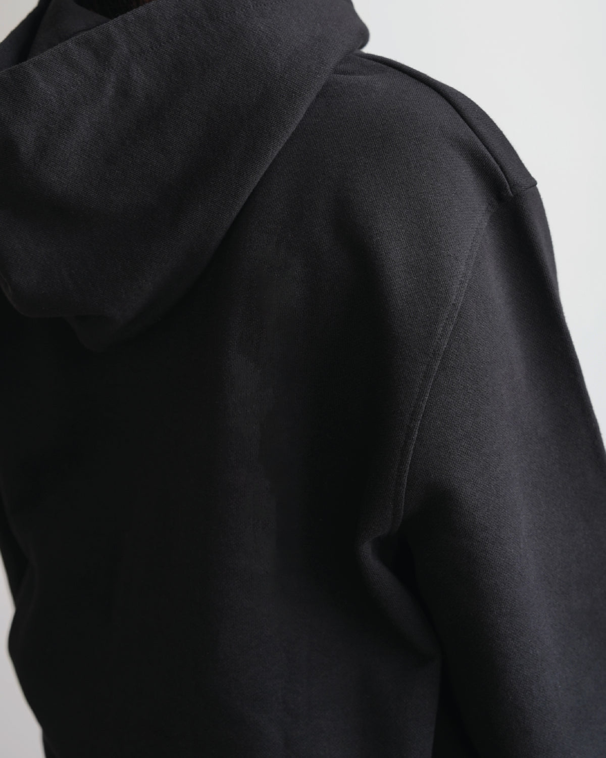 Black hoodie, back view showing the hood and shoulder