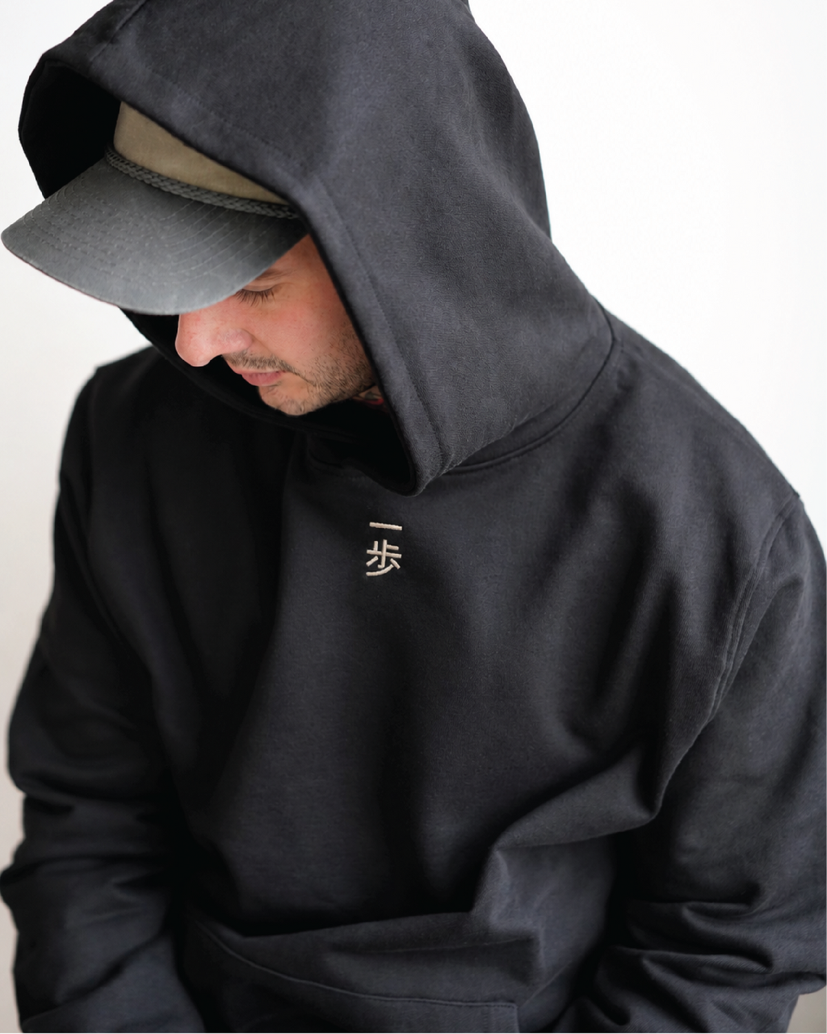 KyoPace Hoodie in Black, worn with the hood up over a cap