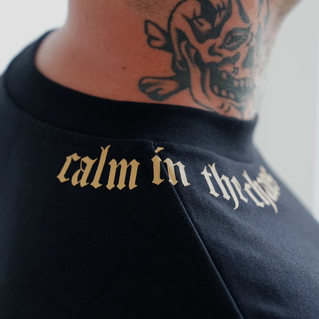 Back collar detail of black boxy cropped t-shirt with gold graphic lettering