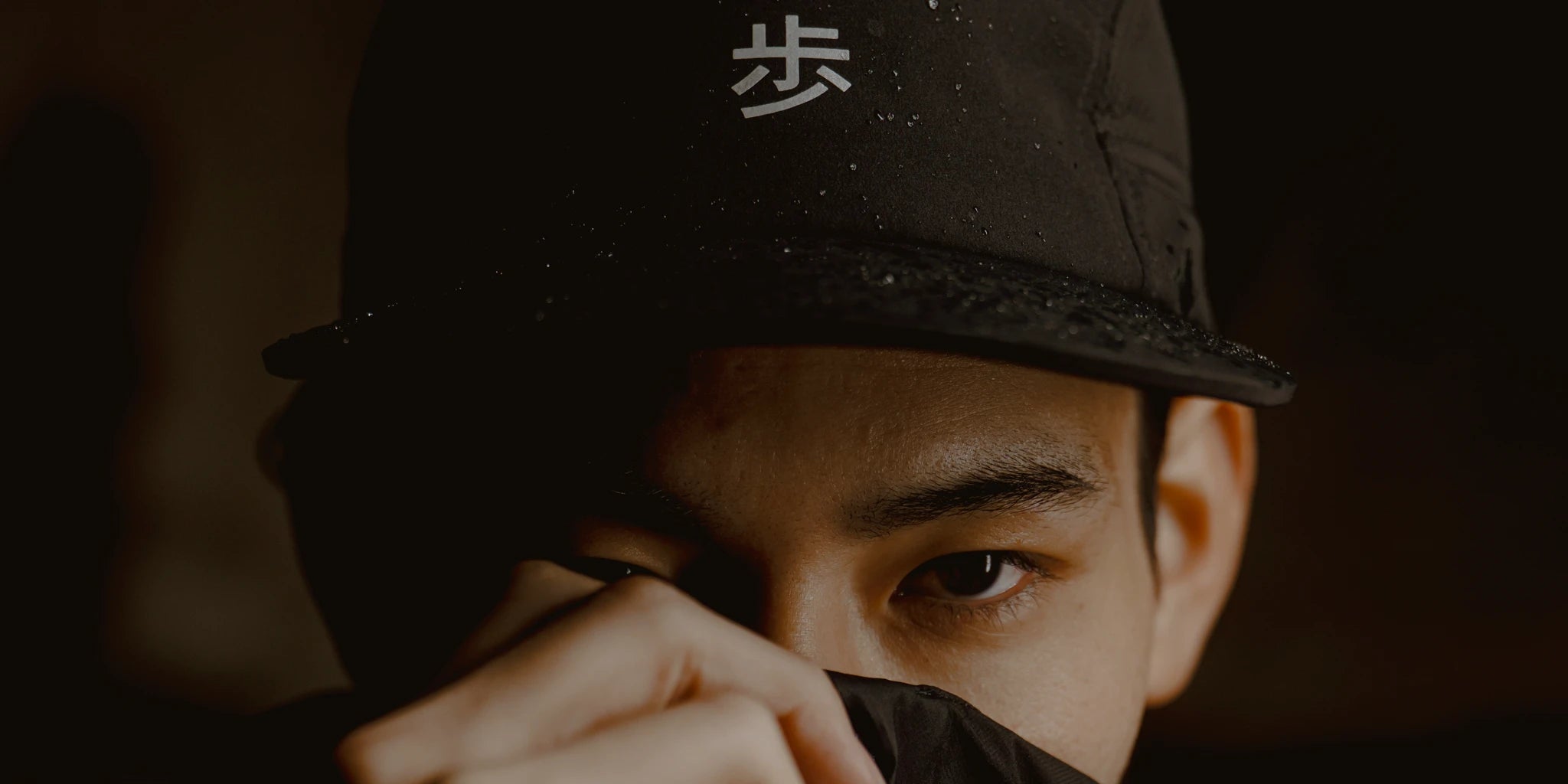 Black performance running cap with reflective Japanese character detail, worn in low light with water-resistant fabric texture visible, ODAAT KyoPace collection hero image.