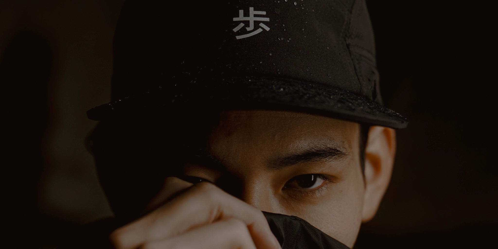 Black performance running cap with reflective Japanese character detail, worn in low light with water-resistant fabric texture visible, ODAAT KyoPace collection hero image.
