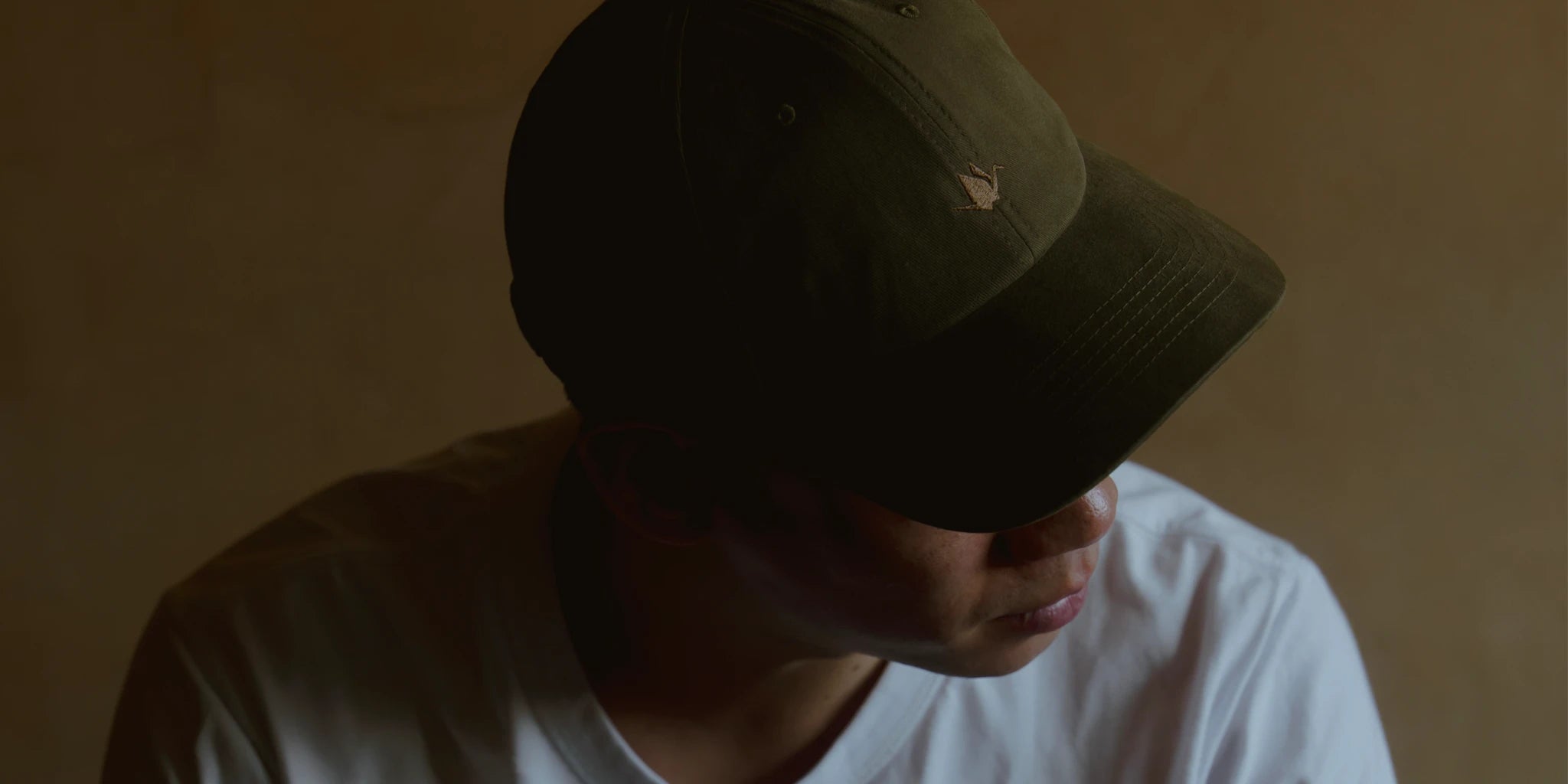 Olive dad cap with tonal crane embroidery, soft curved brim and brushed cotton texture, ODAAT Signature Cap in low light.
