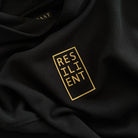 Detail photo of the Resilient Hoodie’s raised tactile print reading ‘RESILIENT’ in a boxed layout—designed for daily, physical affirmation. Made of 100% Organic cotton.