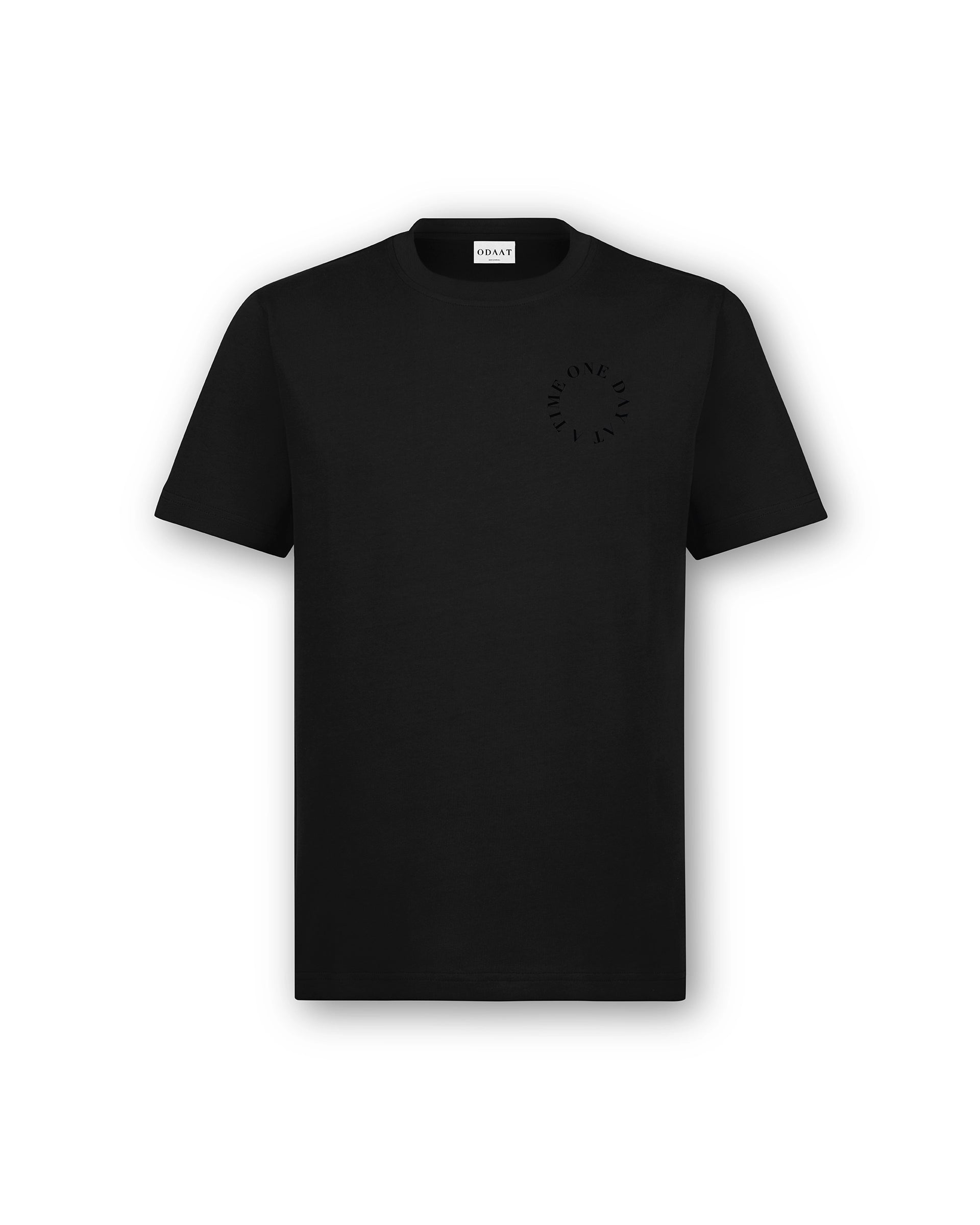 Front of Circle of Resilience Tee in Obsidian with a tonal black-on-black circle design on the left chest, spelling ‘One Day At A Time.’