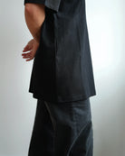 Midweight Tee in Black, side view, worn with dark trousers