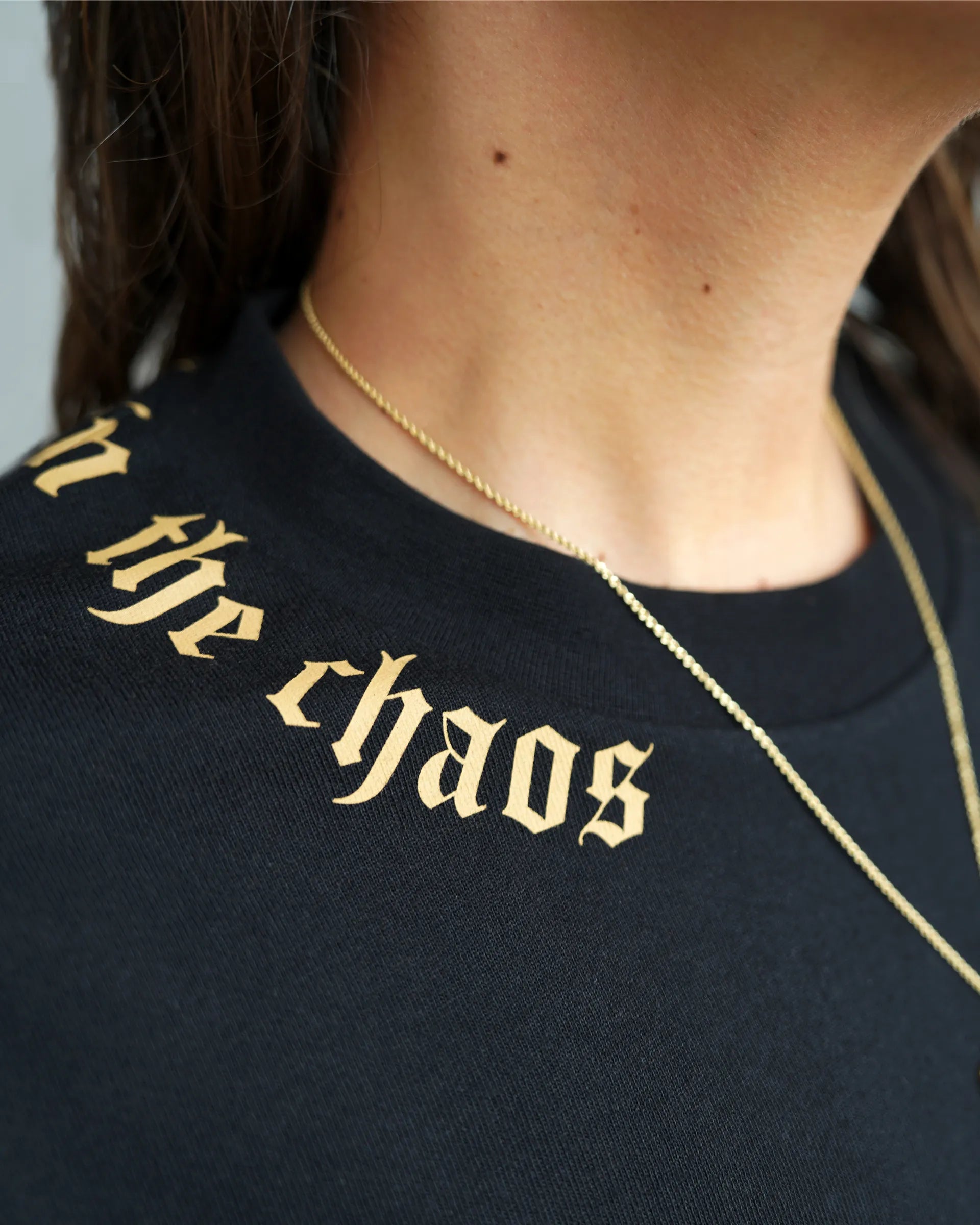 Calm in the Chaos boxy cropped tee in black with gold neckline graphic, front close-up