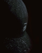 Black KyoPace running cap with crane logo, close-up detail with water droplets on fabric