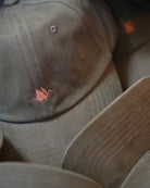 ODAAT Icon Cap in Olive, stacked caps showing the brushed cotton, curved brim and copper Orizuru embroidery.