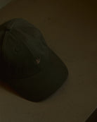 olive signature dad cap close-up showing curved brim and panel construction, soft cotton fabric with crane embroidery, minimal product detail shot with warm neutral background