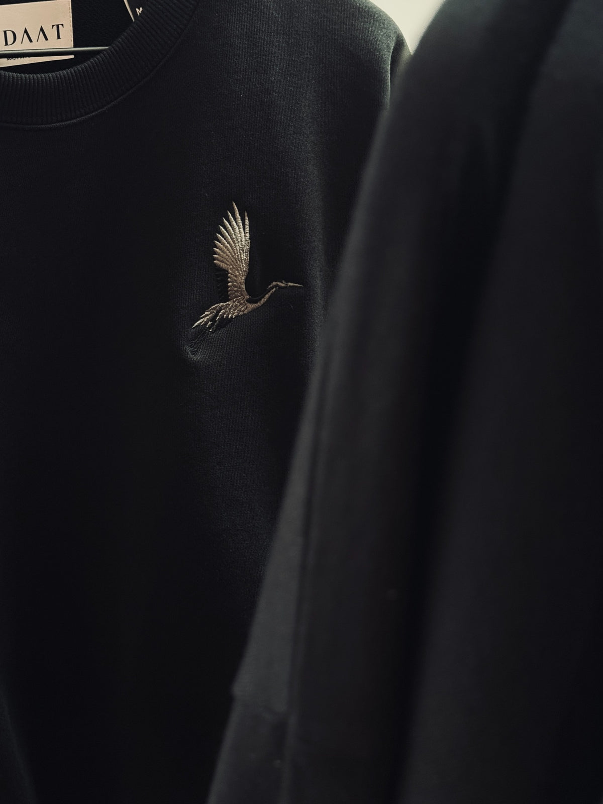 Origami Echo Crewneck with detailed pale crane embroidery on dark fabric
