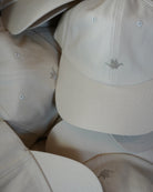 ODAAT Icon Cap in Rice Paper, stacked caps showing the brushed cotton, curved brim and tonal Orizuru embroidery.