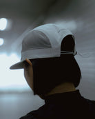 Rear view of model wearing white KyoPace running cap showing mesh panels and adjustable cord