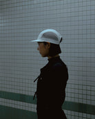 Side profile of model wearing white KyoPace running cap against tiled wall